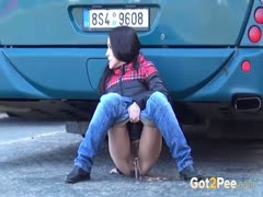 At the bus depot, a dirty-minded brunette with long hair pulls down her trousers to urinate.